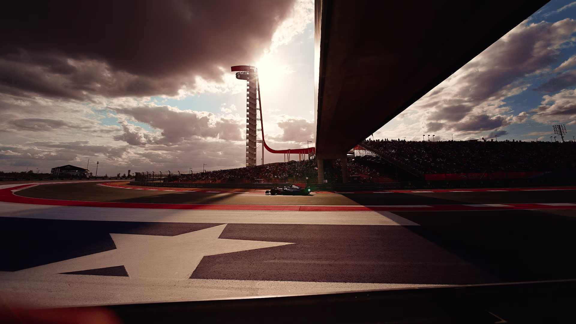 Formula 1 car on track at Circuit of the Americas beneath the observation deck, a Texas star painted on the apron